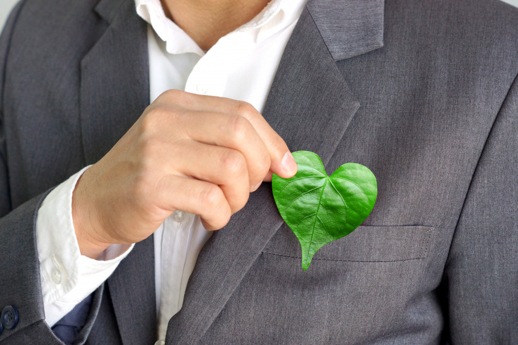 businessman holding heart-shaped leaf concept of sustainability