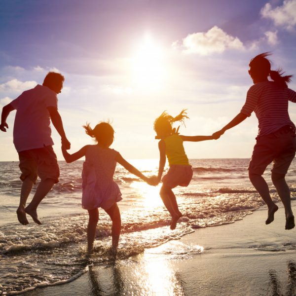 a family with two children jumping on the beach at sunset