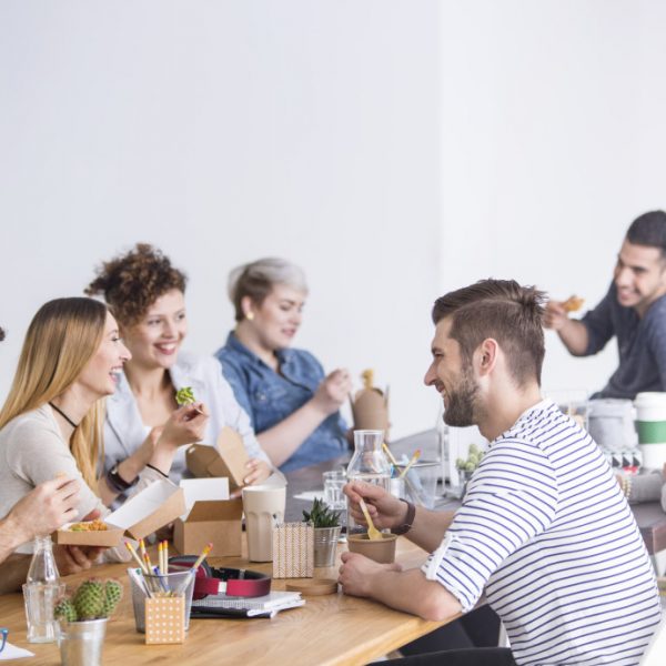 Multicultural team of coworkers eating a healthy lunch together at the office