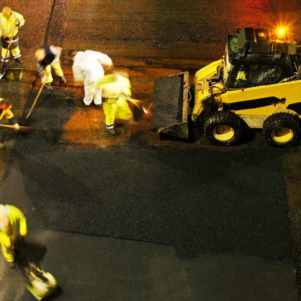 Construction workers working on a road at night